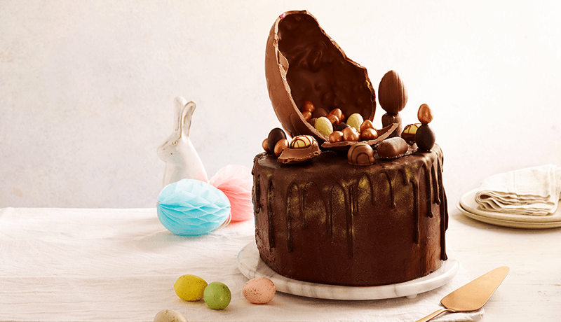 chocolate overload cake topped with cracked chocolate egg shell filled with mini easter eggs