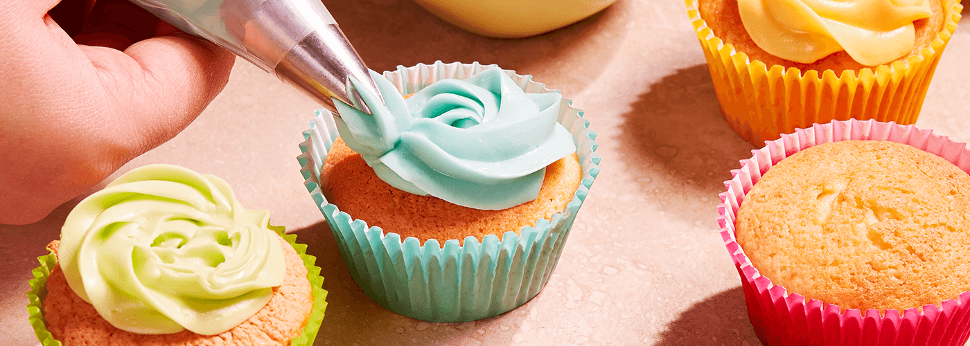 a person doing icing on a cupcake