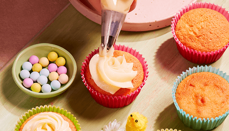 a person doing frosting on cupcakes