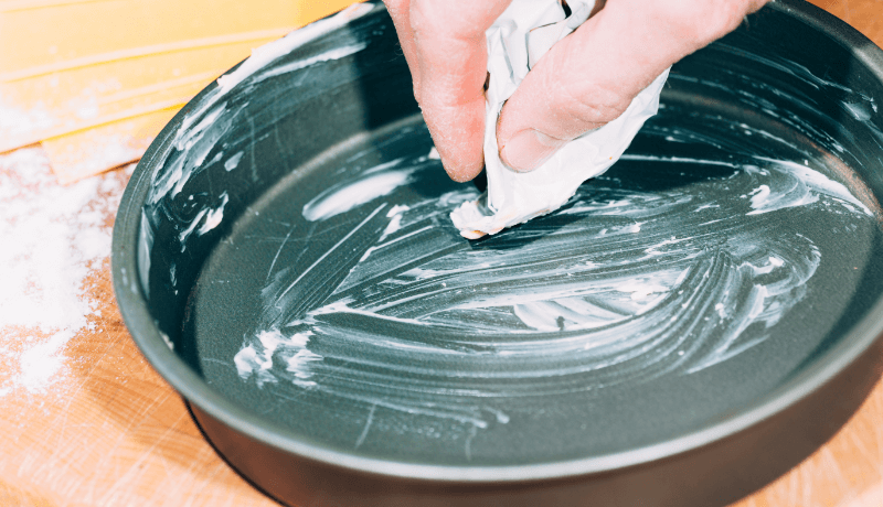 a person greasing baking pan with butter